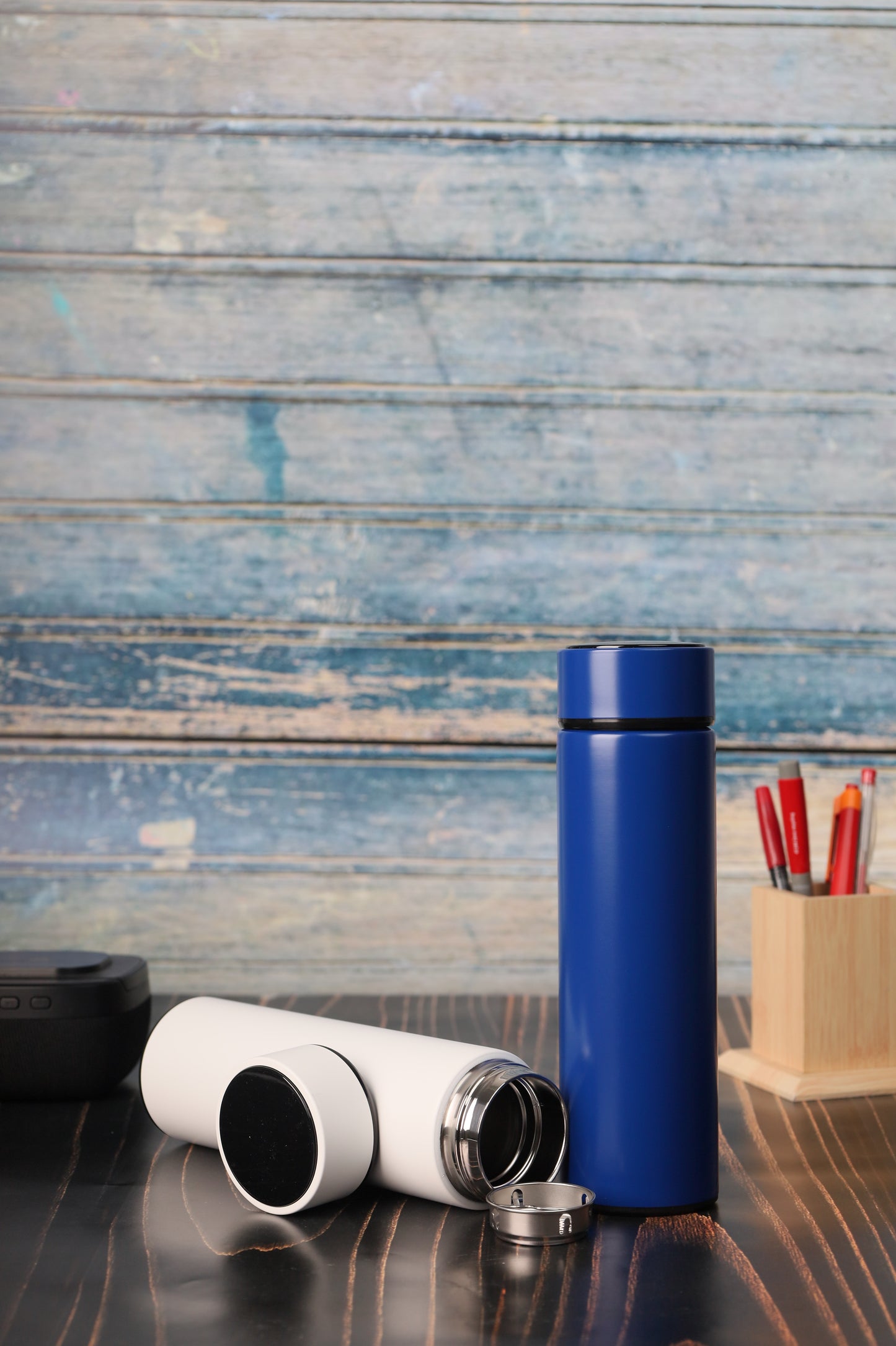Blue and white Double Wall Thermometer Bottle 500ml displayed on wooden table near pencil holder and speaker